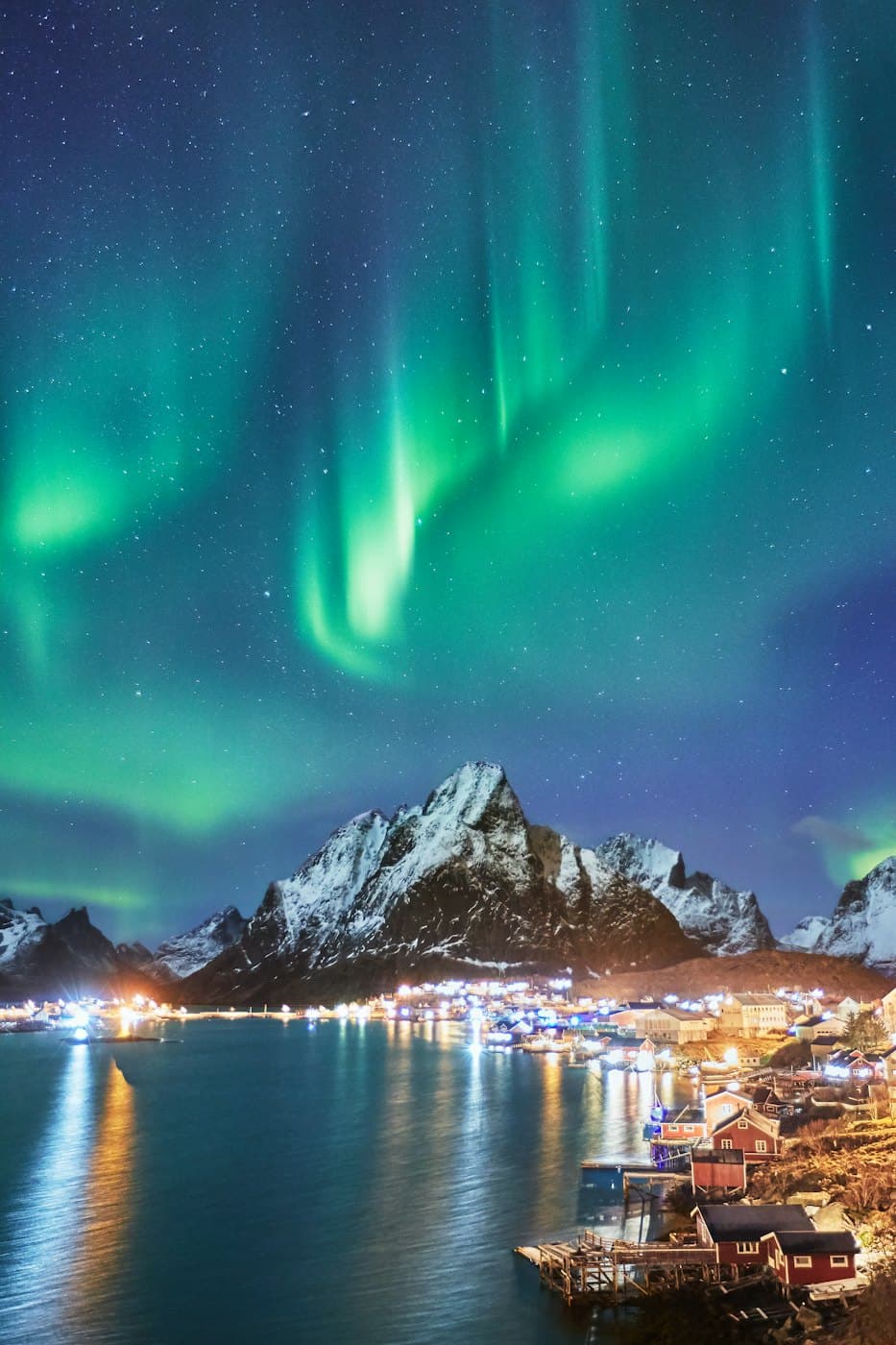 Green northern lights over snowy peaks